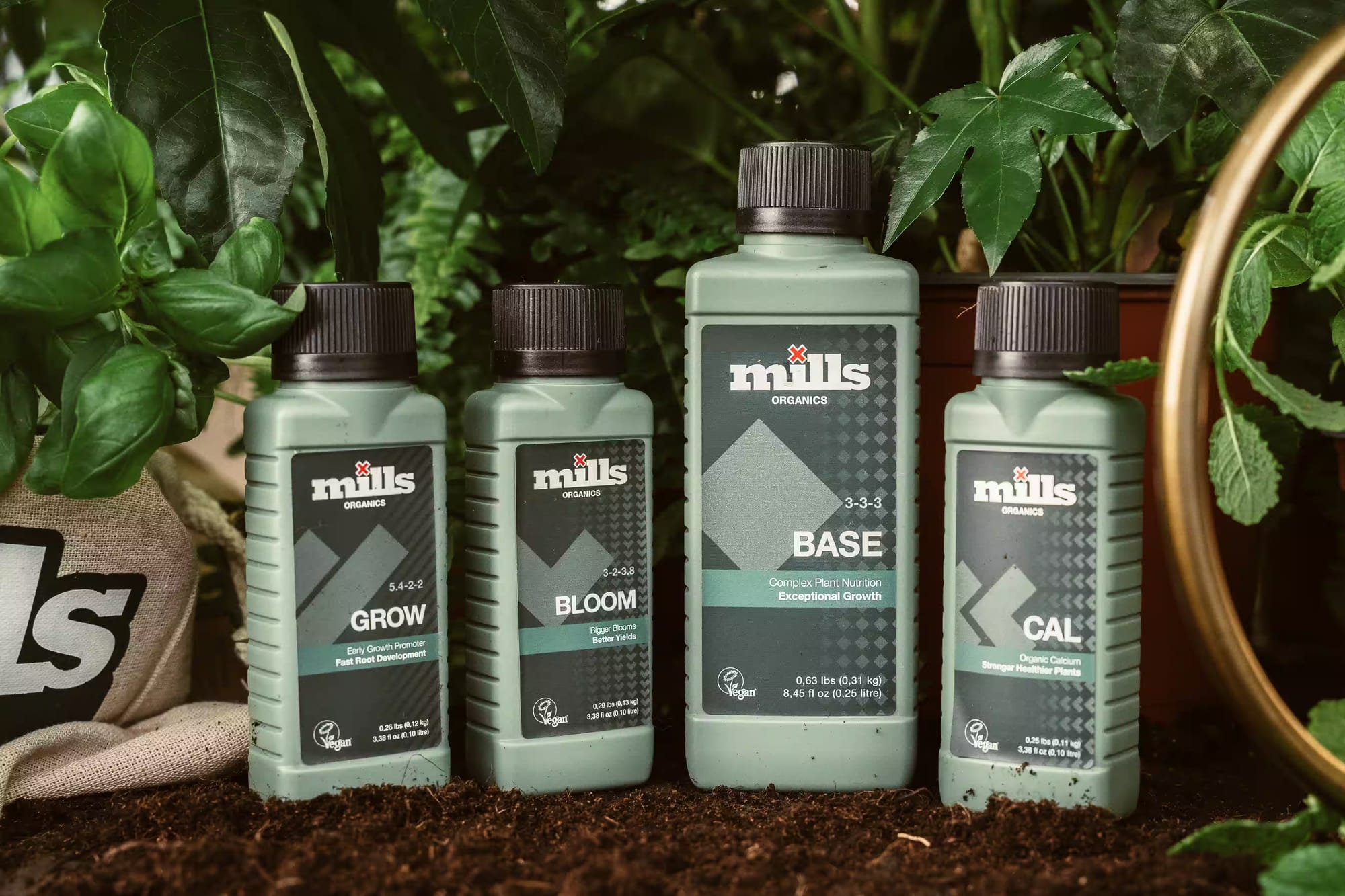 Mills Organics bottles on soil between green plants