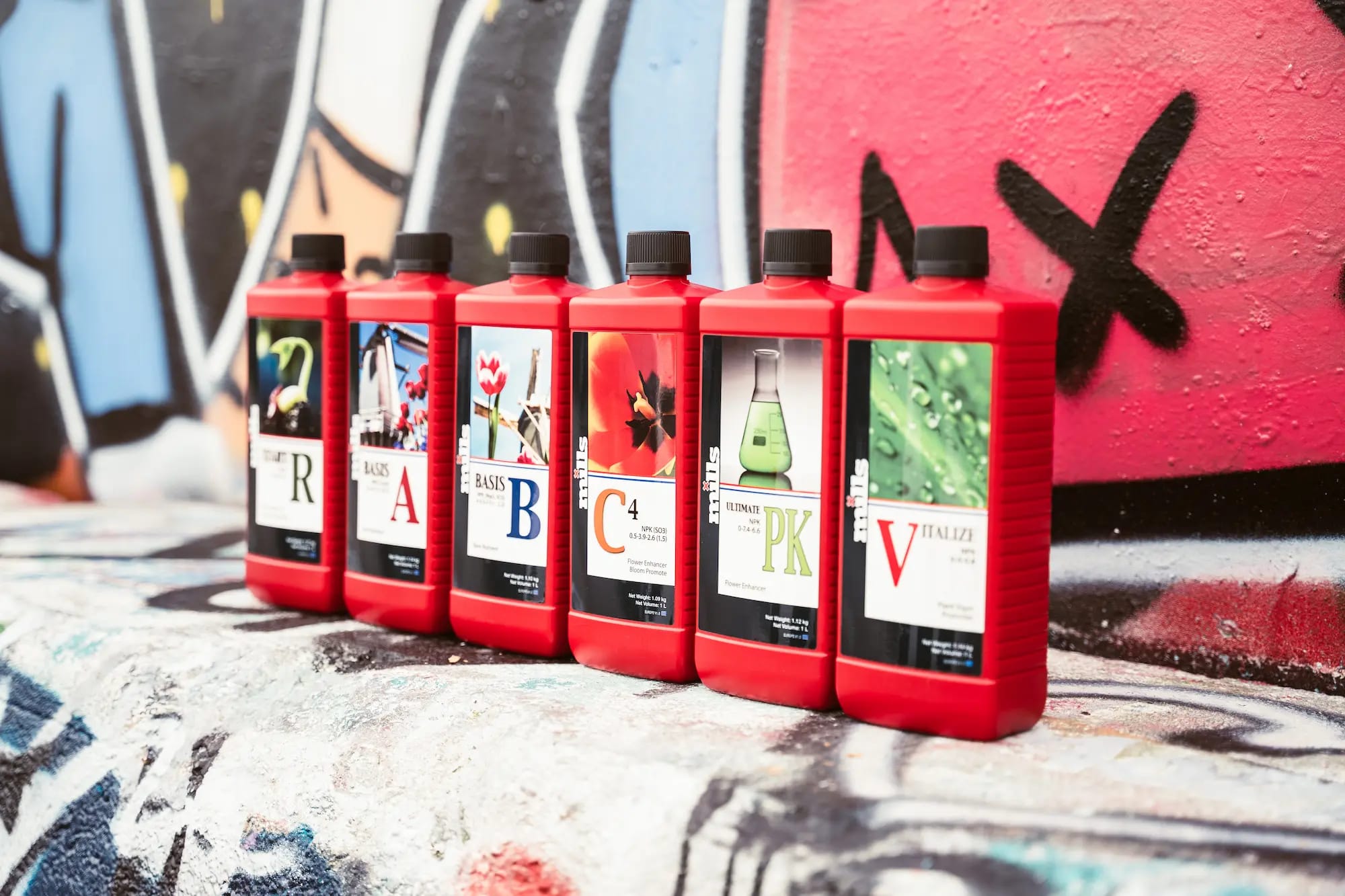 Six bottles of Mills nutrients in front of a graffiti wall with a sprayed X